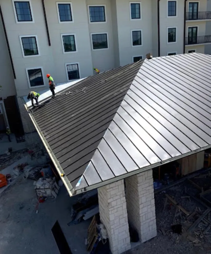 Crew installing standing seam metal roof panels on a commercial project in Lehi